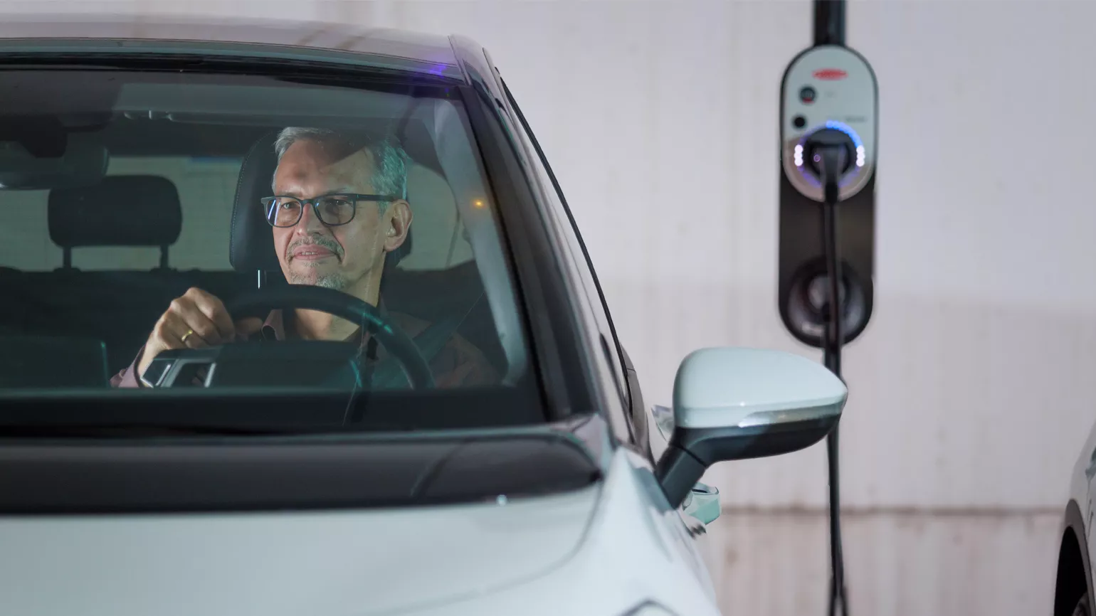 Man in e-car with charging station in the back