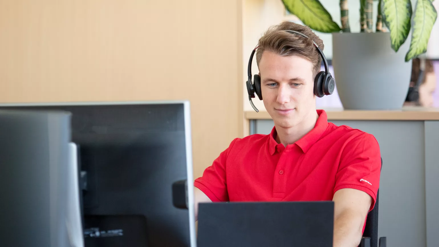 Man with headset sitting in front of laptop